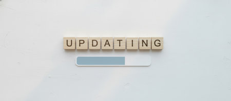 Wooden letter blocks spell updating above a progress bar on a clean white interface, symbolizing software updates, downloads, system upgrades, installation, and digital progressの素材