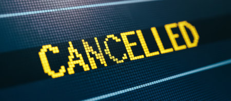 Airport screen displaying the word cancelled in bright yellow pixels, symbolizing travel disruption, flight delays, and unexpected changes to travel plansの素材