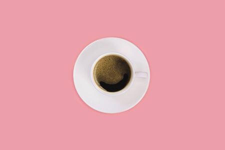Cup of espresso on a white saucer on a pink background. Top view, flat lay, copy spaceの写真素材