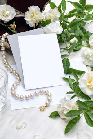 Mockup poster, invitation flyer or greeting card with white roses on marble background and pearl necklace with silver jewelry box. Wedding stationery. Top viewの写真素材