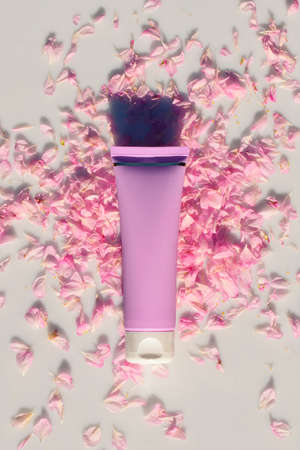 Mockup of a purple tube of moisturizing cream on scattered rose petals, on a gray background in the rays of the sun. Cosmetics. Skin careの写真素材