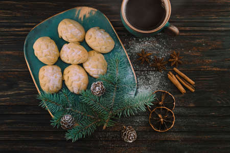 Cookies like cones on a birch-tree plate with spruce sprig and cones, a cup of coffee with spices on a wooden table. Top viewの写真素材