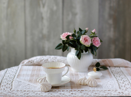Still life with beautiful bouquet of tiny pink roses in white porcelain sugar bowl, coffee cup, home made marshmallow, old-fashioned linen tablecloth with lace, vintage style. Neutral bachground.の写真素材
