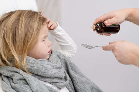 little girl is sick, drink medicine from a spoonの写真素材