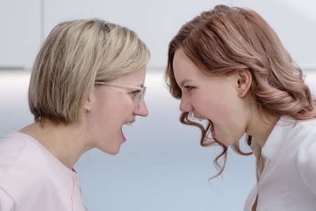 Mom and her teen daughter shout at each other forehead. Relationship problems, transitional periodの写真素材