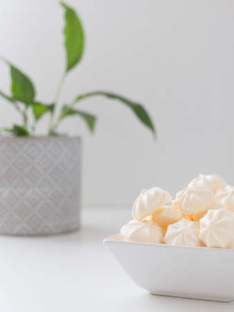 cream meringues in a square bowl on a white backgroundの写真素材
