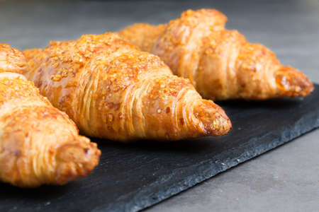 three tasty croissants on black stone background. French food. Close up. Low keyの写真素材