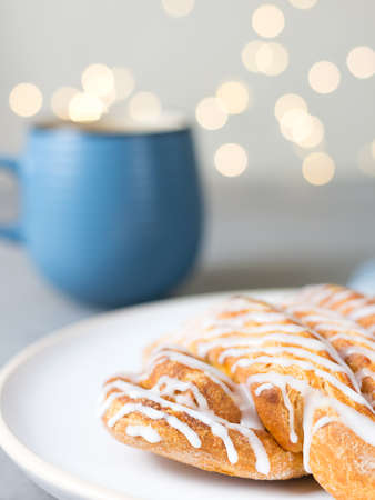Cinnamon roll or cinnamon bun Dessert on plate with blue cup of coffee. Classic American or French bakeries. Bokehの写真素材