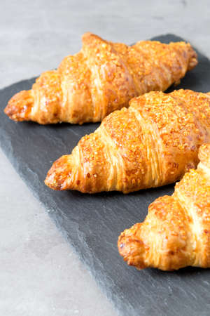 three tasty croissants on black stone background. French food. Close up. Low keyの写真素材