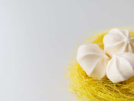 meringues in a yellow basket nest on a white backgroundの写真素材