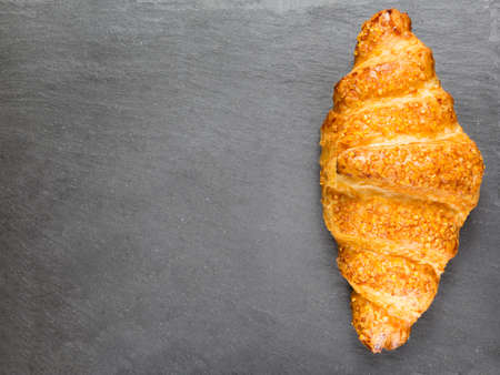 tasty croissant on black stone background. French food. Copy space. Low keyの写真素材
