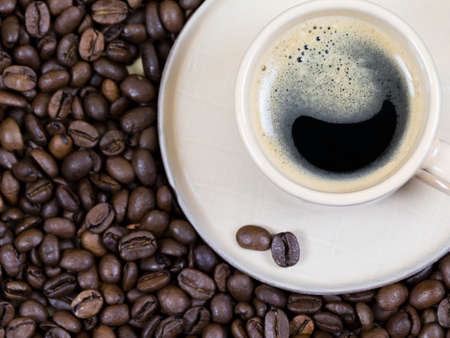 a cup of coffee on the background of coffee beans. View from aboveの写真素材