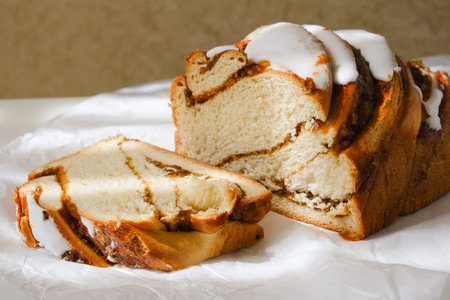 Cinnamon roll or cinnamon bun Dessert with cut off part white paper. Sunshine and shadows. Close upの写真素材