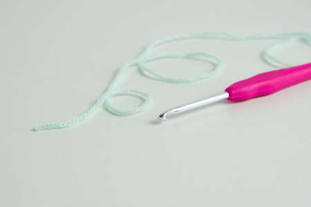 knitting pink crochet hooks and woolen thread on a blue backgroundの写真素材