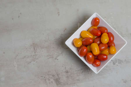 red and yellow small tomatoes in white square bowl. Flatlyの写真素材