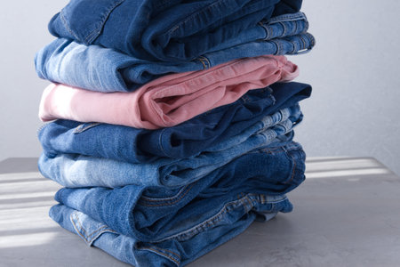 a pile of blue and pink jeans on a gray background. Close up