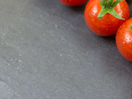 red tomatoes on black stone background. Close up.の写真素材