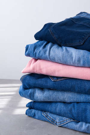 a pile of blue and pink jeans on a gray background. Close upの写真素材