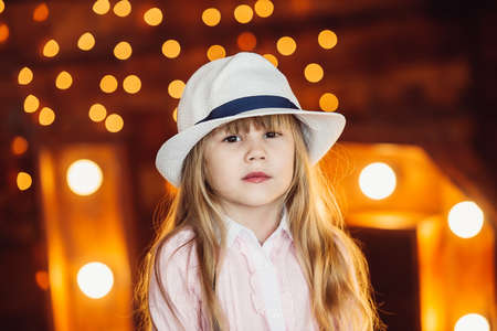 A little girl looks out from behind the wooden letters decorated with lamps and smiles.の写真素材