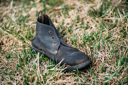 A single black vintage shoe on the green grass. Retro shoes.