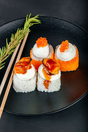 Set of sushi on a black plate on a black background. Decorated with a sprig of rosemaryの写真素材