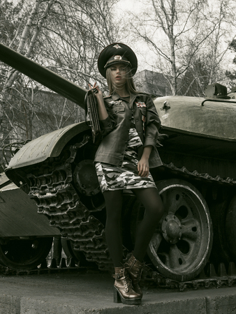 girl in uniform against the background of military equipmentの写真素材