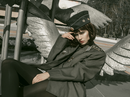 girl in uniform against the background of military equipmentの写真素材