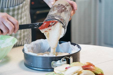 A woman preparing food in a bowl on a cutting board with a cakeの写真素材