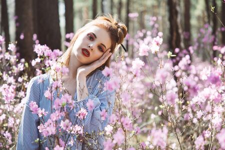 A girl dressed in Japanese style in a flowering forest among pink flowersの写真素材