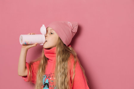 Little girl in pink clothes and a medical mask on a pink background