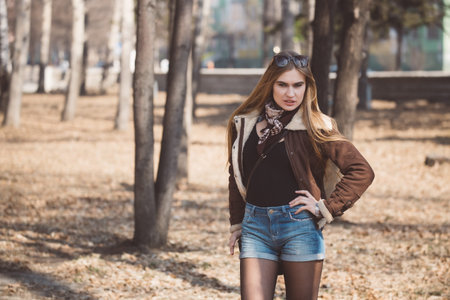 Beautiful girl with long hair walks and poses in a city park in early spring or autumn