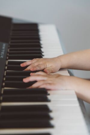 A little girl in a burgundy suit plays a synthesizerの写真素材
