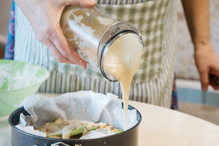 A woman preparing food in a bowl on a cutting board with a cake