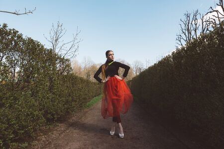 Girl in a red tutu in a city gardenの写真素材