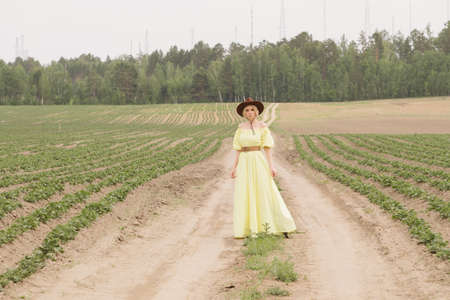 Girl in a cowboy hat and a yellow dress in the fieldの写真素材