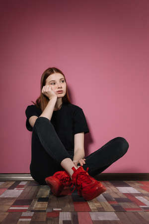 Girl in black poses on a pink background.の写真素材