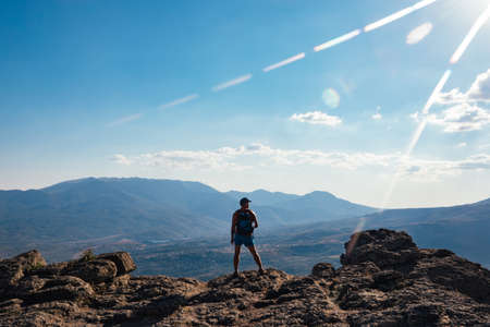 A man tourist stands on a rock against the background of a cliff, mountains and rocksの写真素材