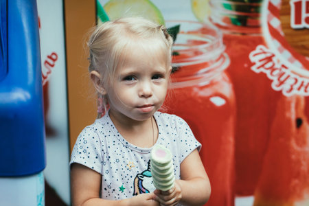 little girl eating bright ice cream on the street.