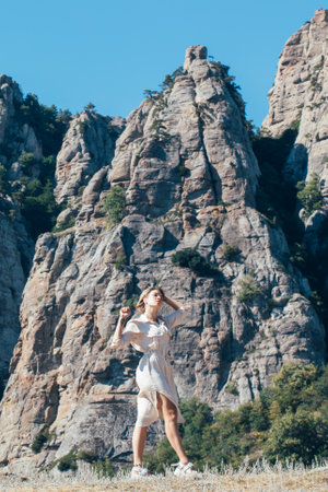 Young woman, girl tourist in safari dress on the rocks in the mountains on a background of blue skyの写真素材