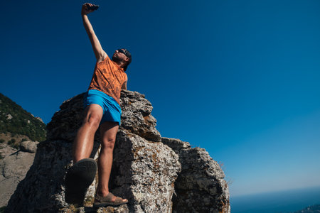 A man tourist stands on a rock against the background of a cliff, mountains and rocksの写真素材