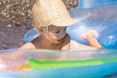 Little girl in a wicker cap floats on an air mattress in the seaの写真素材