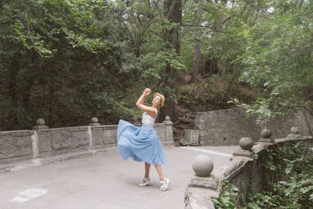 A girl in a blue skirt, white top and hat with a retro camera and a bunch of lavender walks in a beautiful forestの写真素材