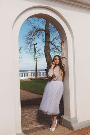 Model girl, ballerina in a white tutu and high heel shoes in a city gardenの写真素材