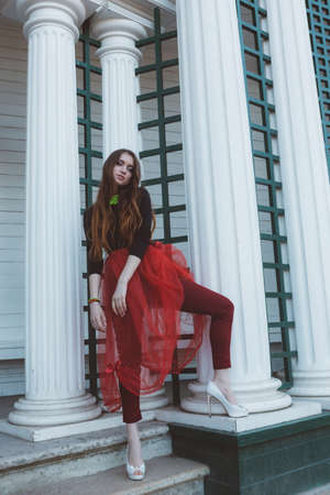 Model girl, ballerina in a red tutu, black turtleneck, high heel shoes in a city gardenの写真素材