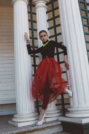 Model girl, ballerina in a red tutu, black turtleneck, high heel shoes in a city gardenの写真素材