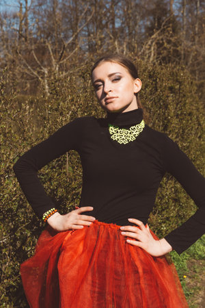 Model girl, ballerina in a red tutu, black turtleneck, high heel shoes in a city gardenの写真素材