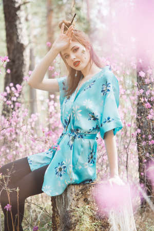 Japanese-style girl in a flowering forest among pink flowers in springの写真素材