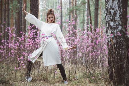 Japanese-style girl in a flowering forest among pink flowers in springの写真素材