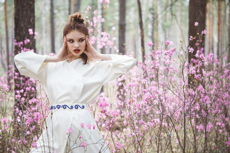 Japanese-style girl in a flowering forest among pink flowers in springの写真素材