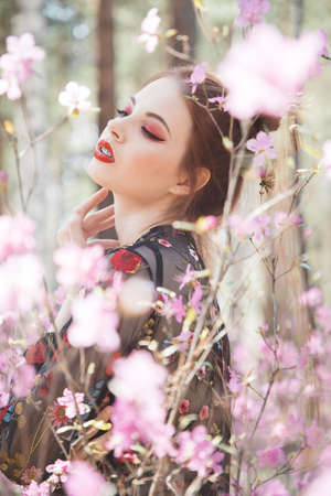 Japanese-style girl in a flowering forest among pink flowers in springの写真素材